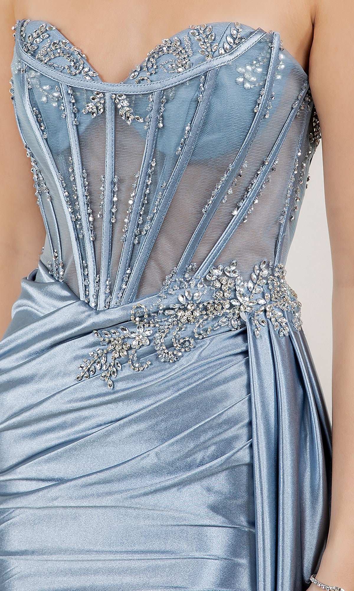 A close-up of the Cinderella Couture 8511J long prom dress with a strapless, light blue sheer corset bodice adorned in silver crystal beadwork and a flowing satin skirt.